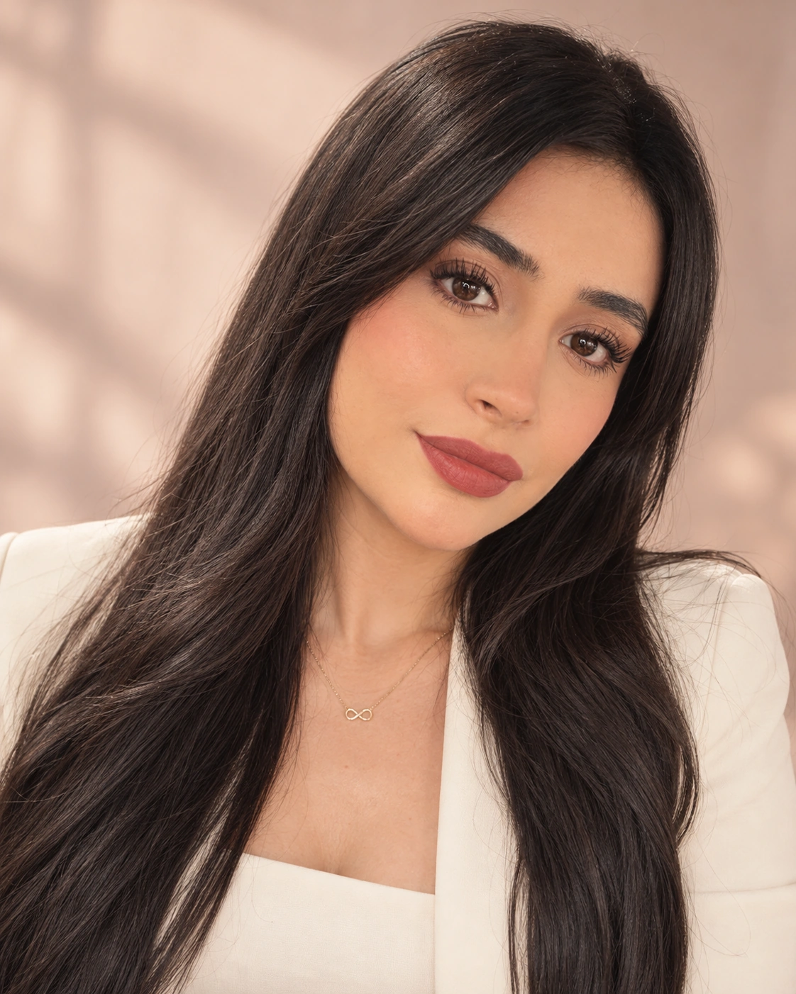 Retrato de mujer con cabello oscuro, maquillaje suave y atuendo blanco